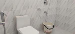 a bathroom with a white toilet and a bucket at Kohuwa Resort in Jyoti Gaon