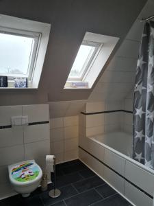 a bathroom with a toilet and a bath tub and skylights at Wunderschöne Ferienwohnung Mit Terrasse Und Garten in Waabs