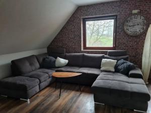 a living room with a couch and a clock on a brick wall at Wunderschöne Ferienwohnung Mit Terrasse Und Garten in Waabs