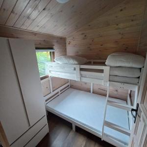 ein Zimmer mit zwei Etagenbetten in einem winzigen Haus in der Unterkunft Domki Słoneczny Brzeg in Dąbki