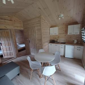 eine Küche mit Tisch und Stühlen in einer Hütte in der Unterkunft Domki Słoneczny Brzeg in Dąbki