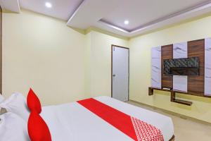 a bedroom with a white bed with red accents at Hotel O Golden in Vadodara +23 photos