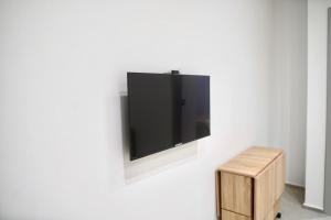 einen Flachbild-TV, der an einer weißen Wand hängt in der Unterkunft Charming S1 cozy modern and bright in Mahdia