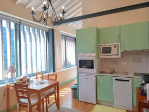 eine Küche mit grünen Schränken und einem Tisch mit einem Esszimmer in der Unterkunft A Arribana in Nordestinho + 14 Fotos