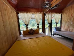 ein großes gelbes Bett in einem Zimmer mit Fenstern in der Unterkunft Cương Mountain View Homestay in Yên Minh