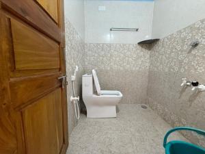 Un baño con inodoro y puerta de madera. en Barefoot and Beyond - Crafted with Kenchas, en Gokarna
