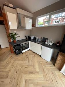 eine Küche mit weißen Schränken und einem Holzboden in der Unterkunft Ferienhaus für 2 Personen  2 Kinder ca 45 m in Wassenaar, Südholland Rotterdam und Umgebung in Wassenaar