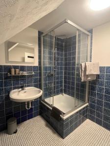 a blue tiled bathroom with a sink and a tub at Apartment Airport Dortmund in Holzwickede