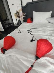 ホーチミン・シティにあるBinh Minh Homstayの白いベッドの上に置かれた2本の赤い傘