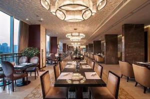 ein Restaurant mit Tischen und Stühlen und einem Kronleuchter in der Unterkunft Wanlin International Hotel in Foshan