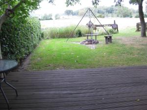 eine Holzterrasse mit einer Schaukel im Gras in der Unterkunft Ferienhaus am See - b44952 in Blankensee