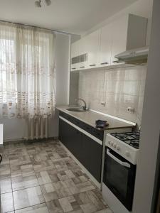 eine Küche mit weißen Schränken und einer Spüle und einem Herd in der Unterkunft Apartament Central Zona Mec in Craiova + 14 Fotos