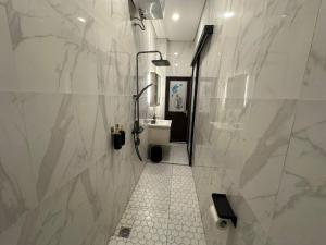 une salle de bain blanche avec une douche et un lavabo dans l'établissement villa koku kuta, à Legian