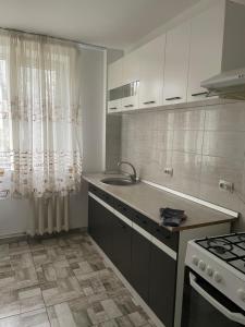 eine Küche mit weißen Schränken und einer Spüle und einem Herd in der Unterkunft Apartament Central Zona Mec in Craiova