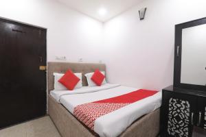 a bedroom with a bed with red pillows and a tv at Metro Regency - Near Lucknow Junction in Lucknow