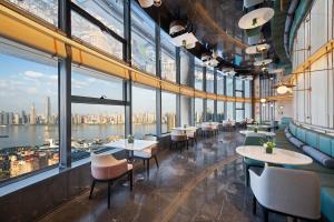 un restaurant avec des tables et des chaises et de grandes fenêtres dans l'établissement Atour Hotel Wuhan Riverview Jianghan Road Pedestrian Street, à Wuhan