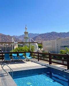a pool with chairs and a lighthouse in the background at Saraya Abdeen Hotel in Aqaba