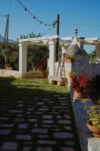 a garden with a stone walkway and a pavilion with flowers at Trulli Pastore in Alberobello +72 photos