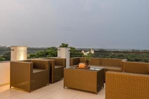 a balcony with brown wicker chairs and a table at SaffronStays Eden Greens in Calangute