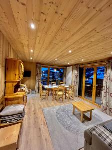 ein Wohnzimmer mit Tisch und Stühlen und Fenstern in der Unterkunft Résidences Delavay La Cordée in Les Gets