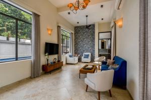 a living room with a couch and chairs and a tv at SaffronStays Eden Greens in Calangute