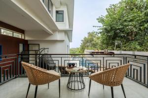 a patio with chairs and a table on a balcony at SaffronStays Eden Greens in Calangute