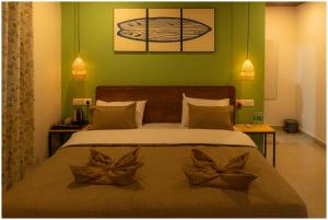 a bedroom with a bed with two bow pillows on it at Lagoon Stays, Gokarna in Gokarna +27 photos