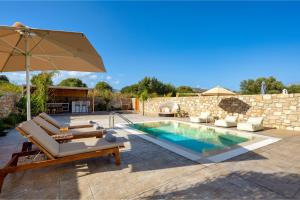 einen Pool mit Stühlen und einem Sonnenschirm neben einer Terrasse in der Unterkunft Amora Pool Villas in Gennadi