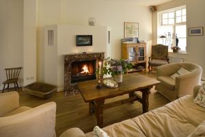 ein Wohnzimmer mit Kamin und Tisch in der Unterkunft Wohnung im zweiten Obergeschoss des Gutshauses in Neuenkirchen