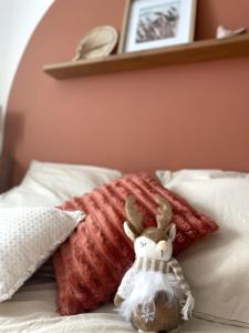 einem gefüllten Kaninchen, das auf einem Bett mit Kissen sitzt in der Unterkunft Le Cocon des rêves studio neuf avec terrasse et Parking in Wintzenheim