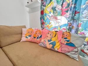ein Sofa mit vier Disney-Prinzessinnen-Kissen darauf in der Unterkunft Chez Alice, Appartement proche de Disneyland Paris in Montry