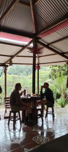 zwei Personen, die an einem Tisch unter einem Schirm sitzen in der Unterkunft Mirador Jungle El Macuti in Rurrenabaque