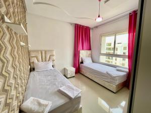 非斯Prestigia Fes Luxury Apartments的有两张床和一扇窗户的卧室