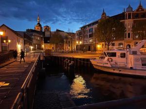 a boat docked in a canal in a city at night at Weisses Traumschloss An Der Ostsee in Hohendorf