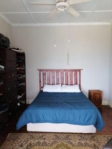 ein Schlafzimmer mit einem Bett mit einer blauen Decke und einem Deckenventilator in der Unterkunft Great sea view, swimming pool, braai, wi-fi in Port Shepstone