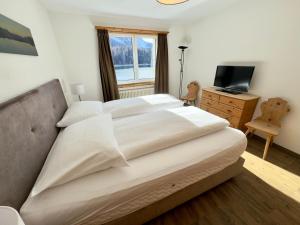 a bedroom with a large bed and a television at Hotel Waldhaus am See in St. Moritz