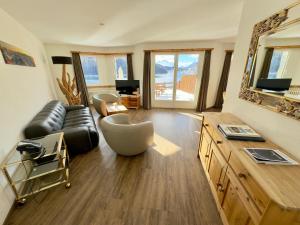 a living room with a leather couch and a television at Hotel Waldhaus am See in St. Moritz