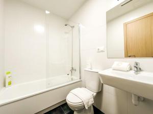 a white bathroom with a toilet and a sink at Apartamento Luzada by ALÔGA in Cee