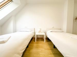 two beds in a room with a table at Apartamento Luzada by ALÔGA in Cee