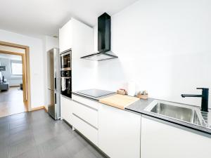 a kitchen with white cabinets and a sink at Apartamento Luzada by ALÔGA in Cee +3 photos