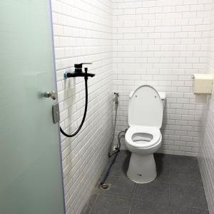 een witte badkamer met een toilet in een stal bij Box me in Bangkok