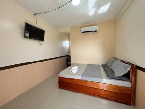 ein kleines Schlafzimmer mit einem Bett und einem Fernseher in der Unterkunft IZZY Resort in Naguilayan