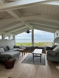 - un salon avec canapés et vue sur l'océan dans l'établissement Sommerhus Med Sjæl Få Skridt Fra Vandkanten, à Martofte