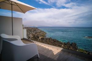 a view of the ocean from a balcony with an umbrella at Islet House in São Roque