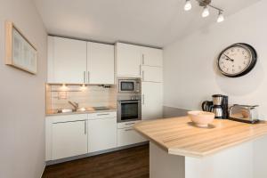 a kitchen with white cabinets and a clock on the wall at Dorfring 36 Seeadler in Stein