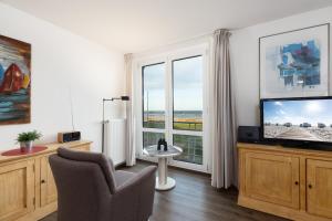 a living room with a tv and a chair and a window at Dorfring 36 Seeadler in Stein