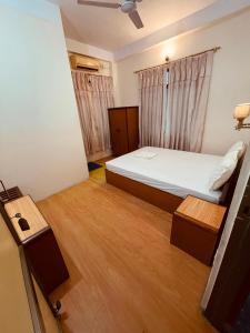 a small bedroom with a bed and wooden floors at New Buddha Bhoomi Guest House in Lumbini