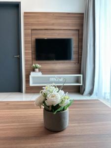 - un vase avec des fleurs blanches sur une table dans le salon dans l'établissement Sunway Onsen Suite Cozy Homestay, à Ipoh