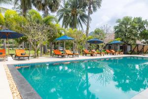 a pool at a resort with chairs and umbrellas at Garto Beach Resort Samui in Ban Thong Phlu