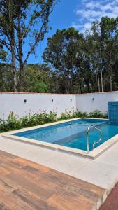 a swimming pool next to a white wall at Aldeia Mar in Bertioga